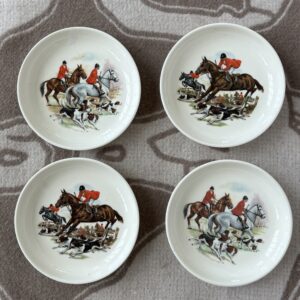 Four decorative plates featuring hunting scenes with riders and dogs.