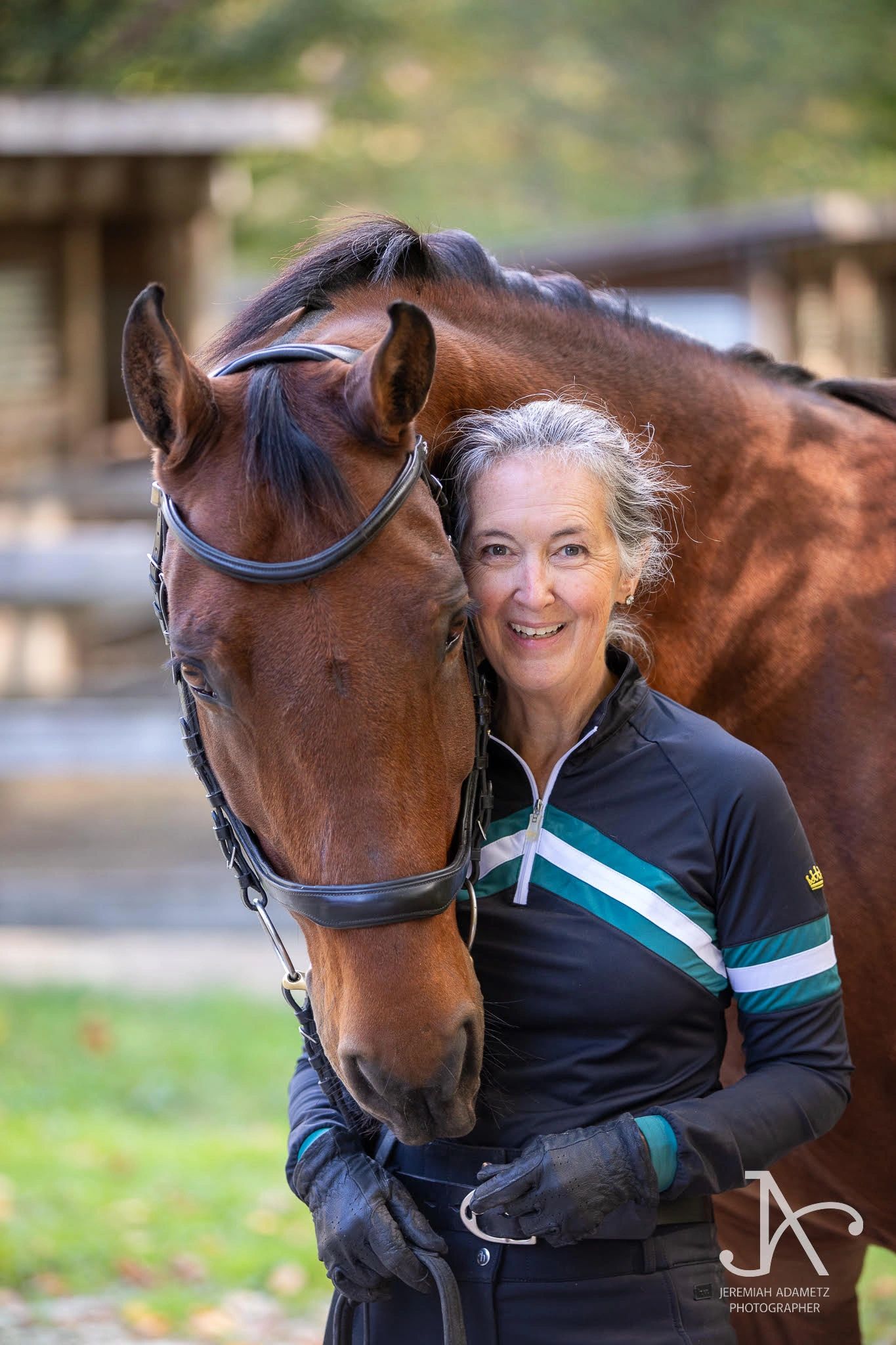 Smiling woman gently hugging a brown horse outdoors.