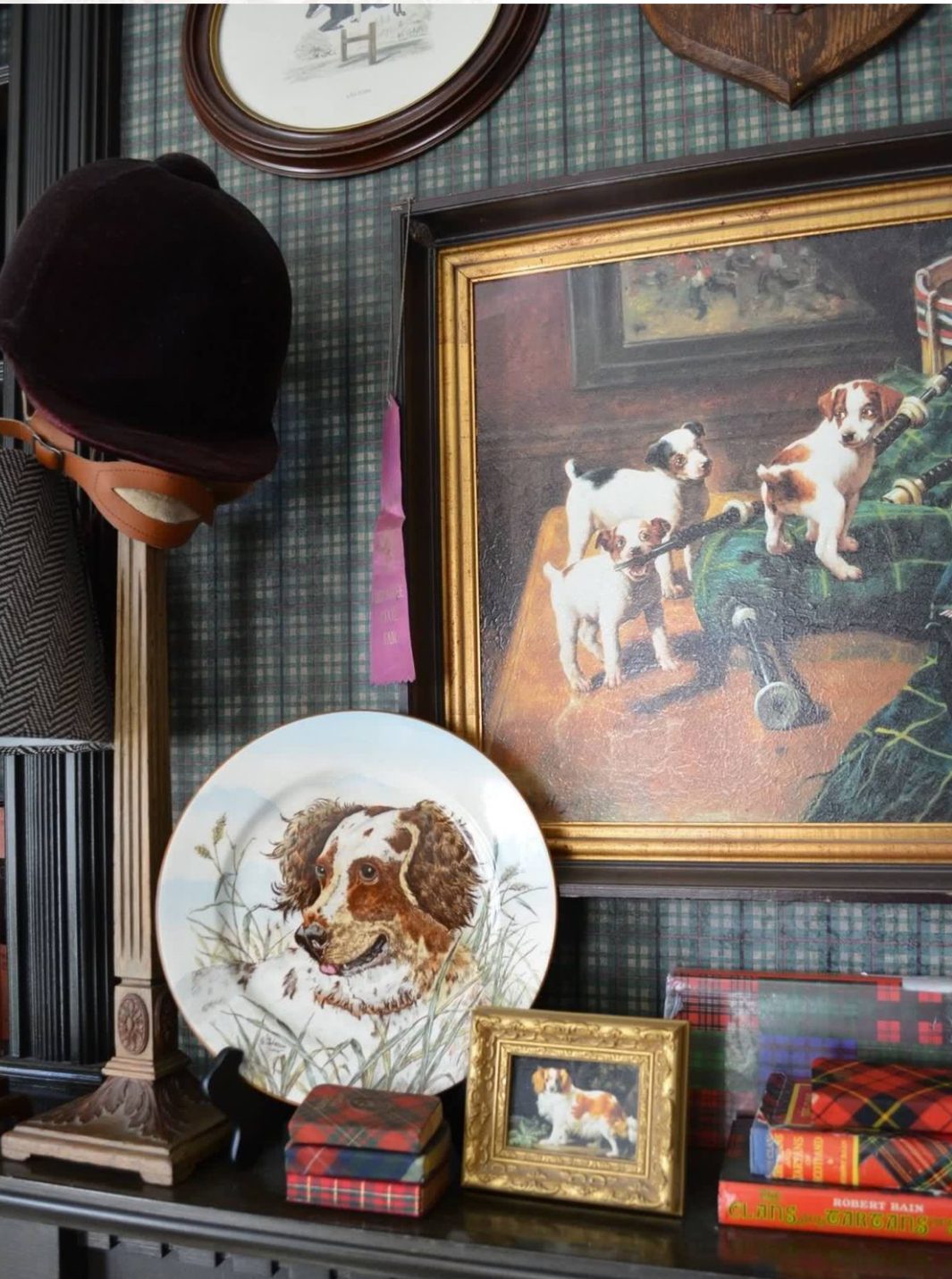 A plate with food, a framed painting, and a hat on a wall.