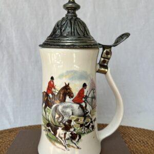 Ornate beer stein with hunting scene and metal lid.