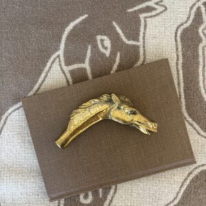 Gold-colored panther brooch on a brown textured card.