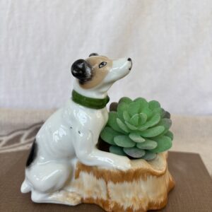 Ceramic dog figurine holding a succulent plant on a wooden base.