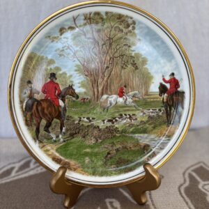 Decorative plate with a hunting scene featuring riders, horses, and hounds.