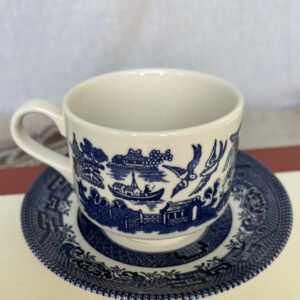 Blue and white porcelain teacup and saucer with intricate scenic design.