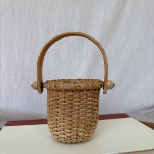 A small woven basket with a curved handle.