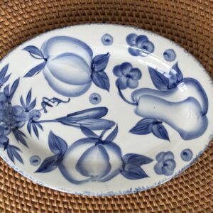 Oval plate with blue fruit and floral design on white ceramic.