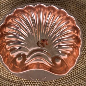 Shiny copper vintage jelly mold with intricate ridges.