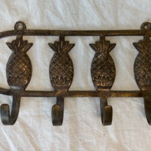 Metal wall hook rack with four pineapple-shaped hooks.
