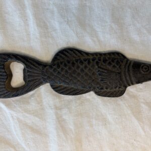 A fish-shaped cast iron bottle opener with intricate detailing.