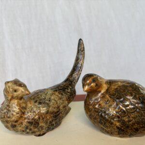Two small ceramic birds with a glossy finish on a white surface.