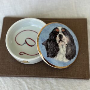 Porcelain trinket box featuring a painted dog portrait and a gold clasp.