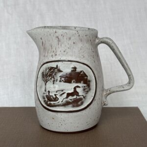 Vintage ceramic pitcher with a hunting scene illustration.